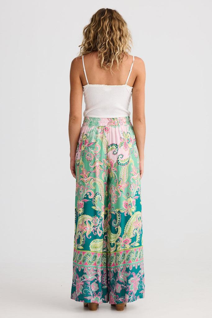 Woman wearing a white top and colorful patterned pants on a white background