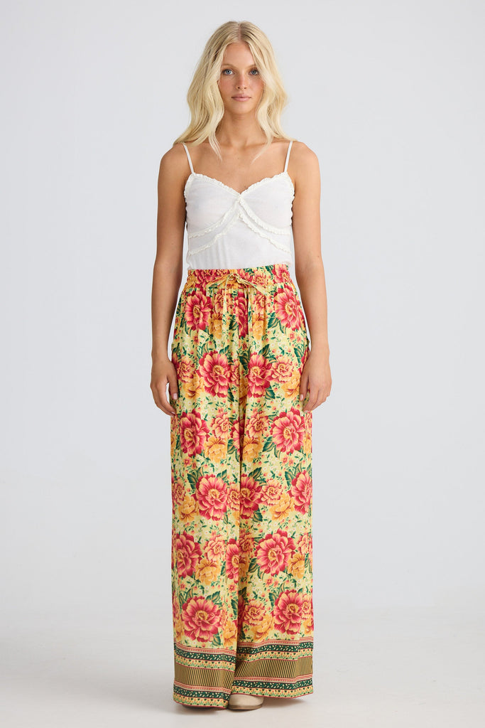 Woman wearing a white top and floral pants on a white background