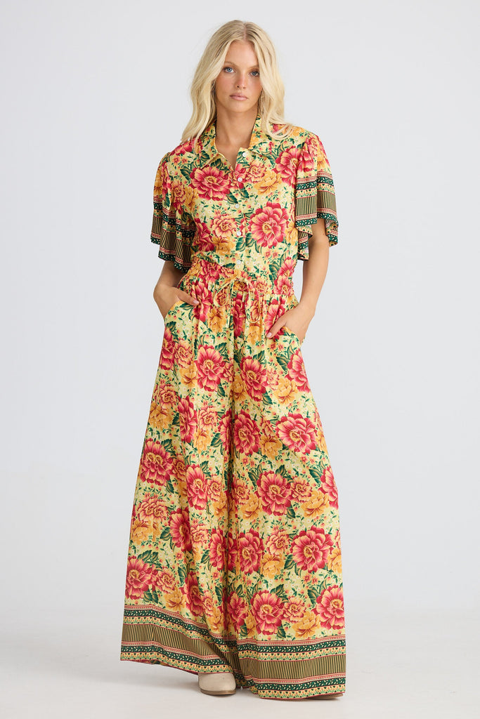 Woman wearing a colorful floral pants and shirt on a white background