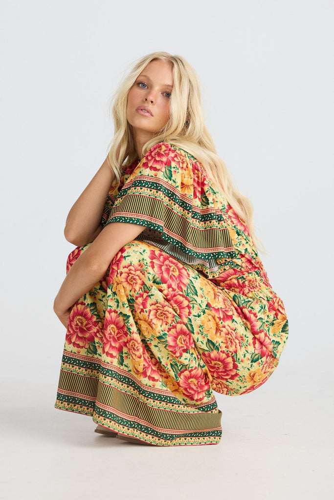 Woman wearing a colorful floral pants and shirt on a white background