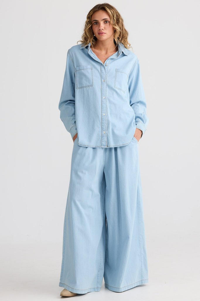 Woman wearing a light blue denim outfit on a white background