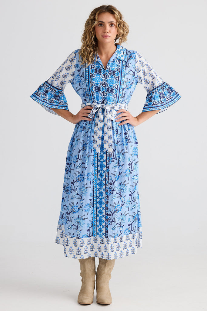 Woman wearing a blue floral dress with bell sleeves on a white background