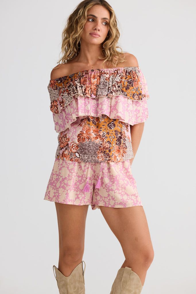 Woman wearing a colorful off-shoulder top and shorts set on a white background