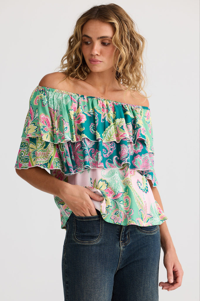 Woman wearing a floral off-shoulder top and jeans on a white background