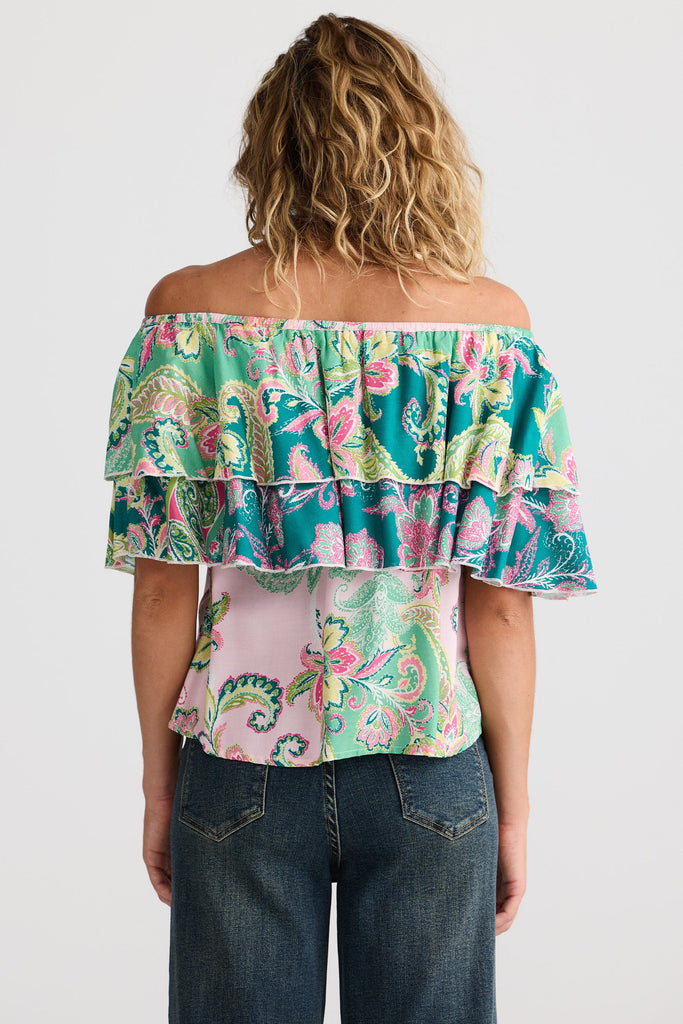 Woman wearing a colorful off-shoulder top with ruffles on a white background