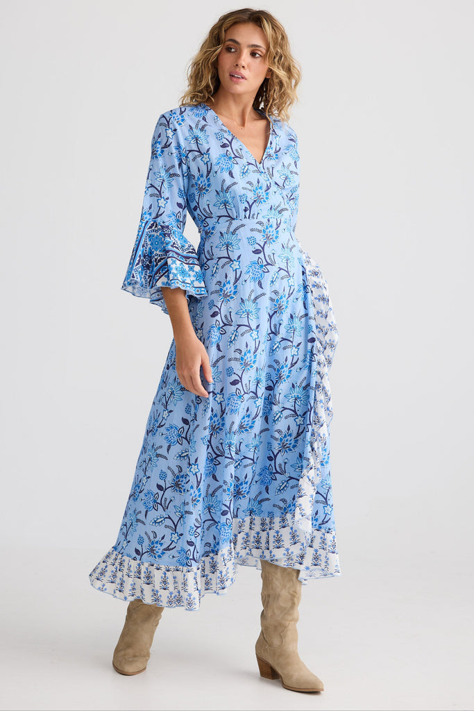 Woman wearing a blue floral dress with beige boots on a white background