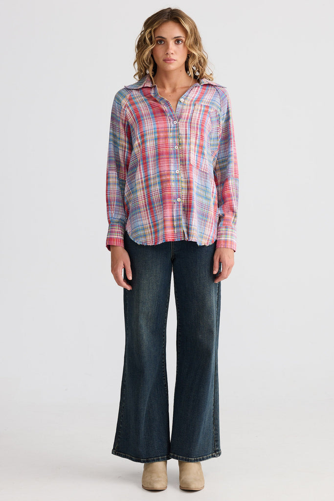 Woman wearing a plaid shirt and dark jeans on a white background