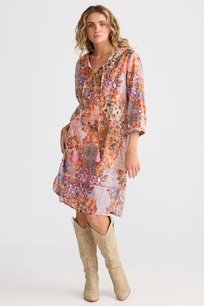 Woman wearing a floral dress with beige knee-high boots on a white background