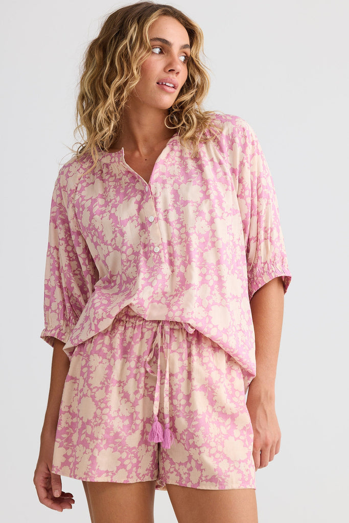 Woman wearing a pink and white floral pajama set on a white background
