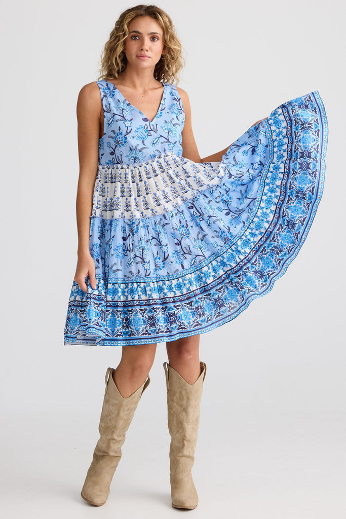 Woman wearing a blue patterned dress with beige boots on a white background