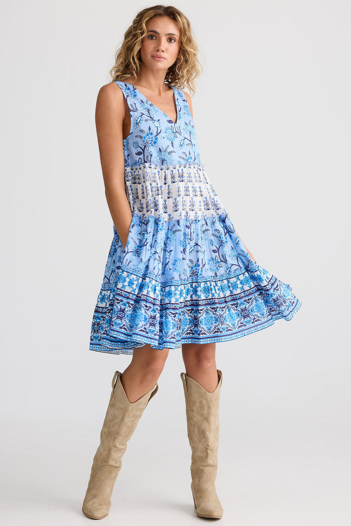 Woman wearing a blue patterned dress with beige knee-high boots on a white background