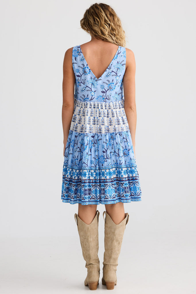 Woman wearing a blue patterned dress with beige boots on a white background