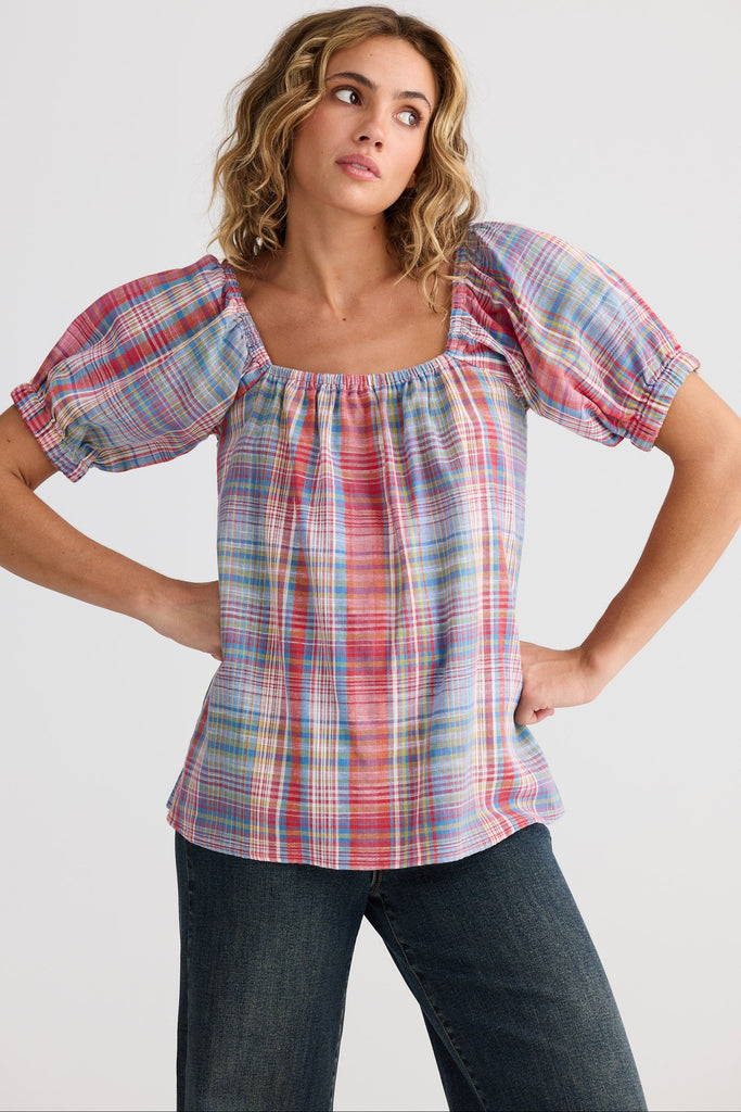 Woman wearing a plaid blouse with puffed sleeves on a white background