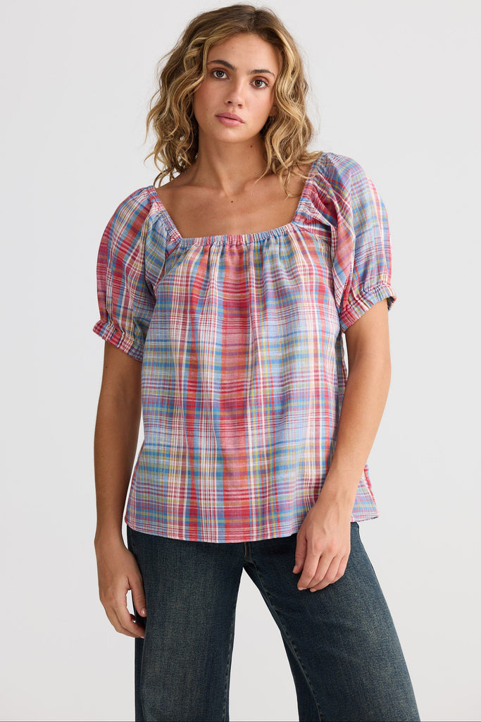 Woman wearing a plaid blouse and jeans on a white background