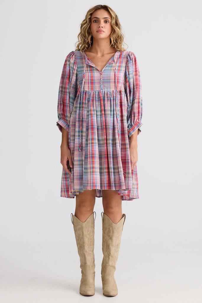 Woman wearing a plaid dress with knee-high boots on a white background