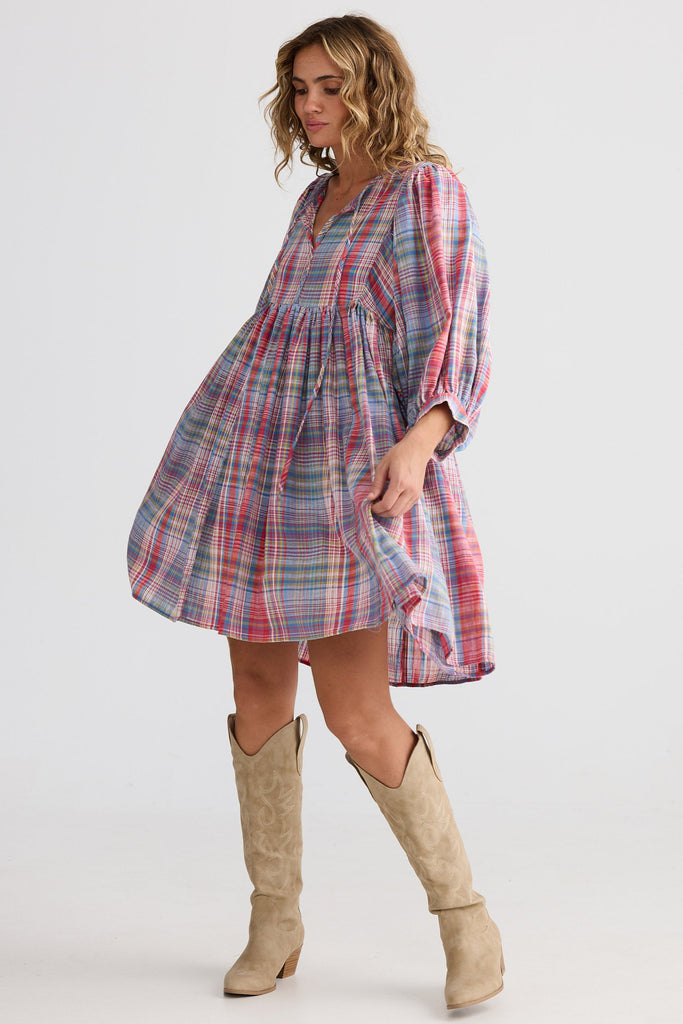 Woman wearing a plaid dress and beige knee-high boots on a white background