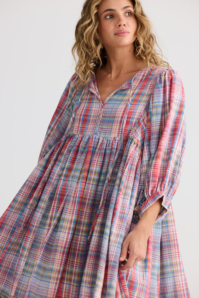 Woman wearing a plaid dress with long sleeves against a white background