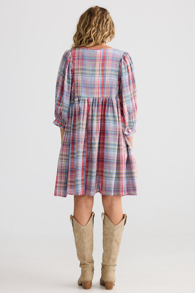 Woman wearing a plaid dress with long sleeves and a white background