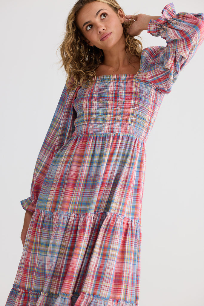 Woman wearing a plaid dress with long sleeves on a white background
