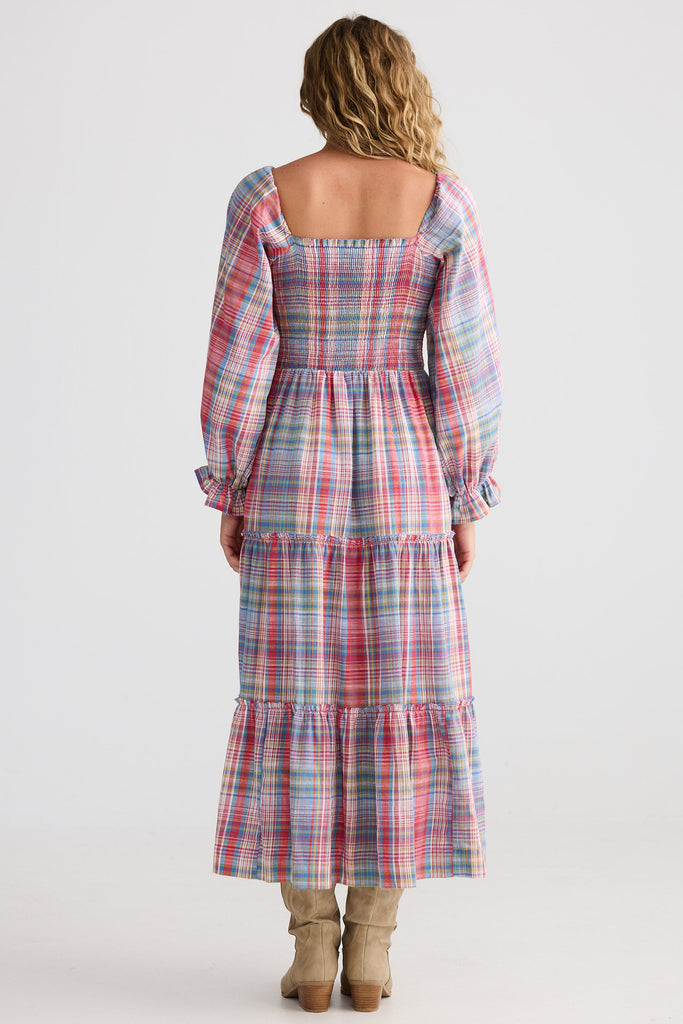 Woman wearing a plaid dress with long sleeves on a white background