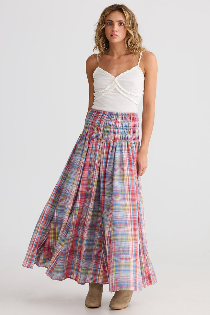 Woman wearing a plaid skirt and white top on a white background