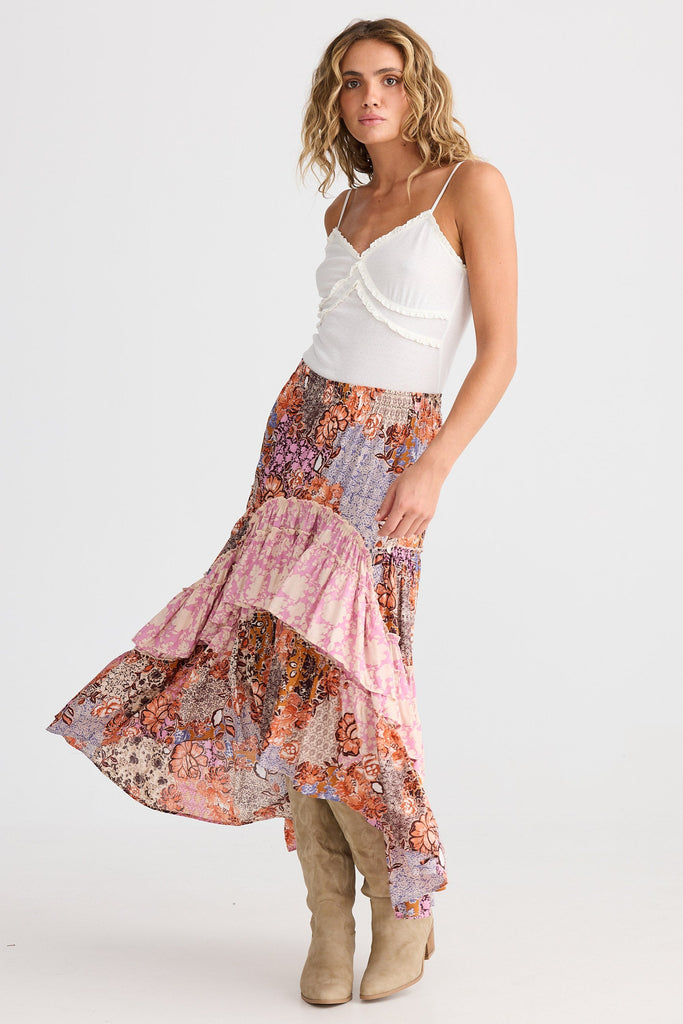 Woman wearing a white top and colorful floral skirt on a white background