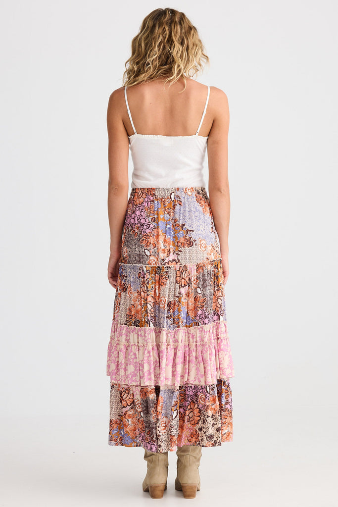 Woman wearing a colorful patchwork skirt and white top on a white background