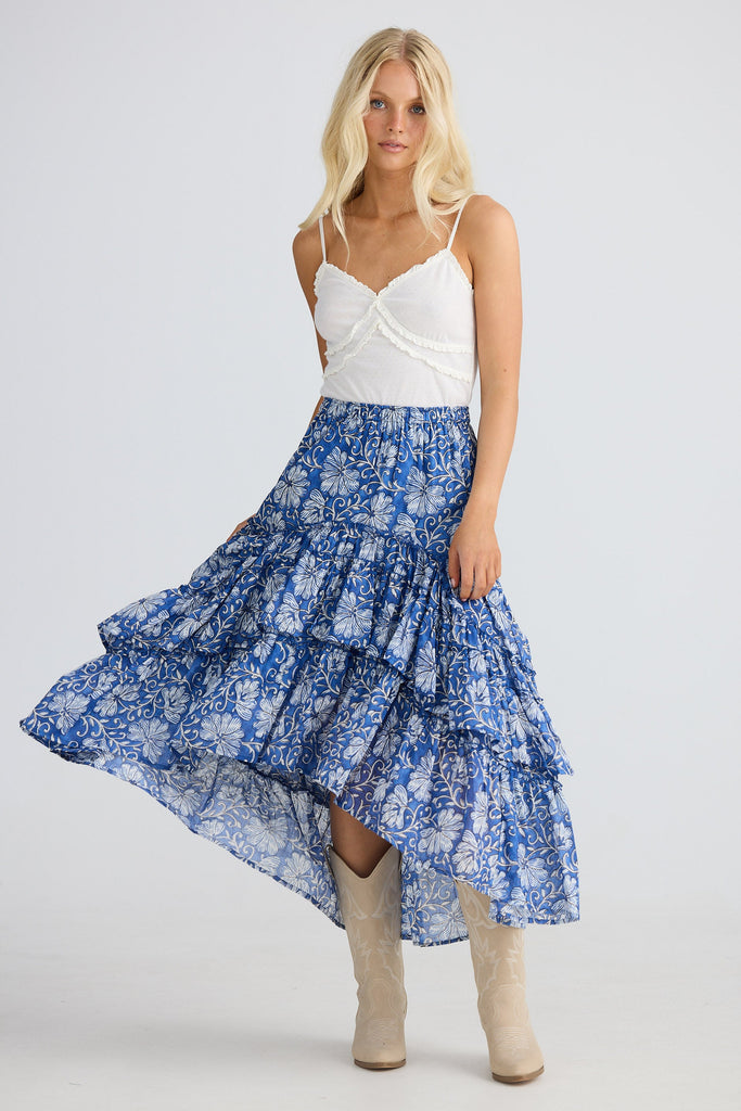 Woman wearing a white top and blue floral skirt on a white background