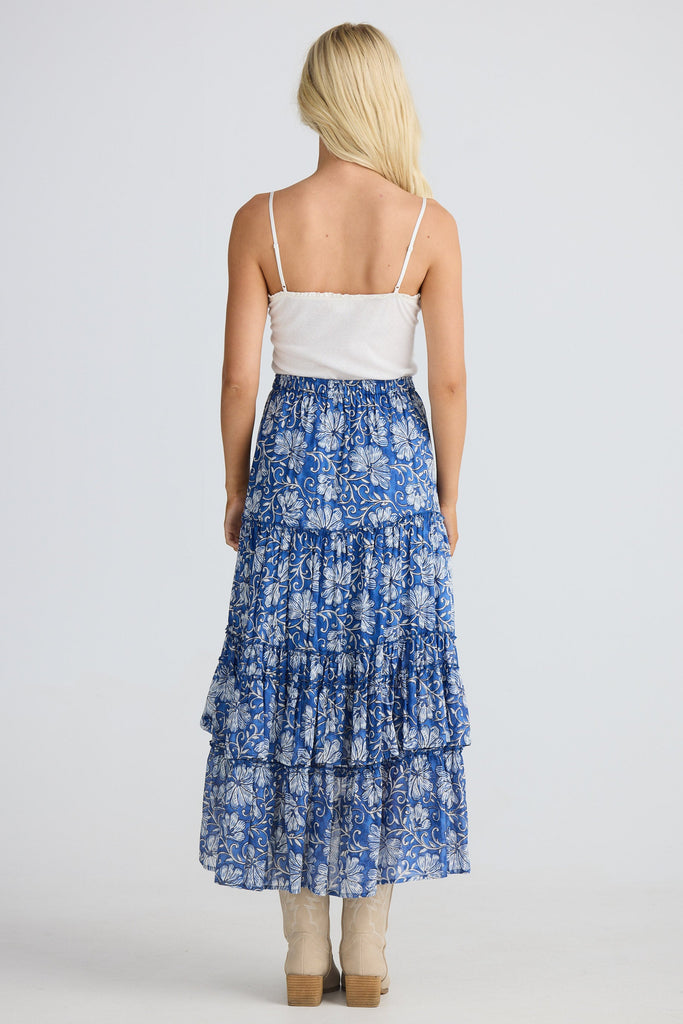 Woman wearing a blue floral tiered skirt on a white background