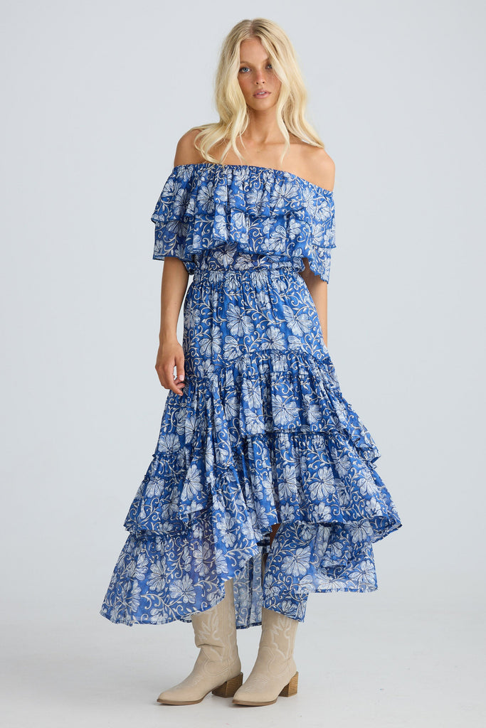 Woman wearing a blue floral off-shoulder top and skirt on a white background