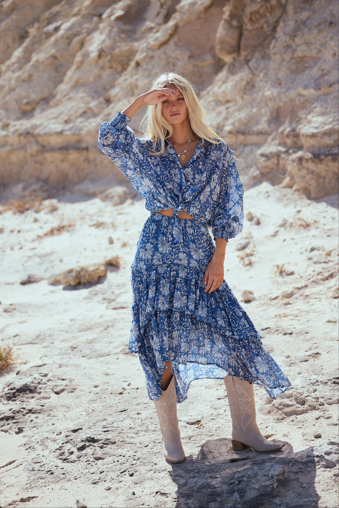 Woman in a blue shirt and skirt standing in a desert landscape