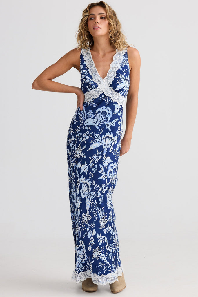 Woman wearing a blue floral dress with white lace details on a white background