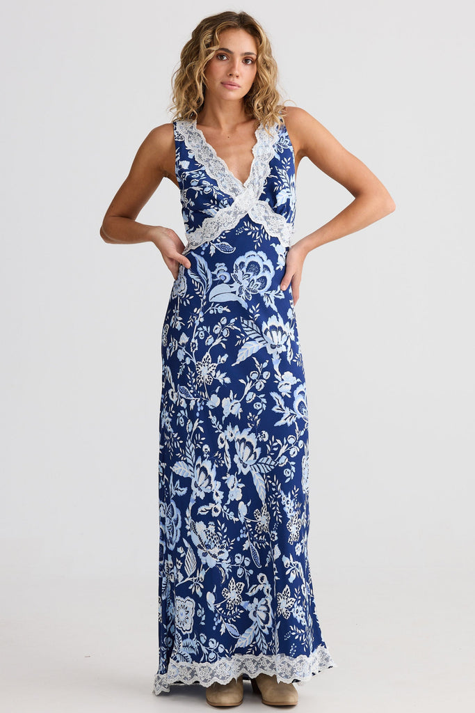 Woman wearing a blue floral dress with white lace details on a white background