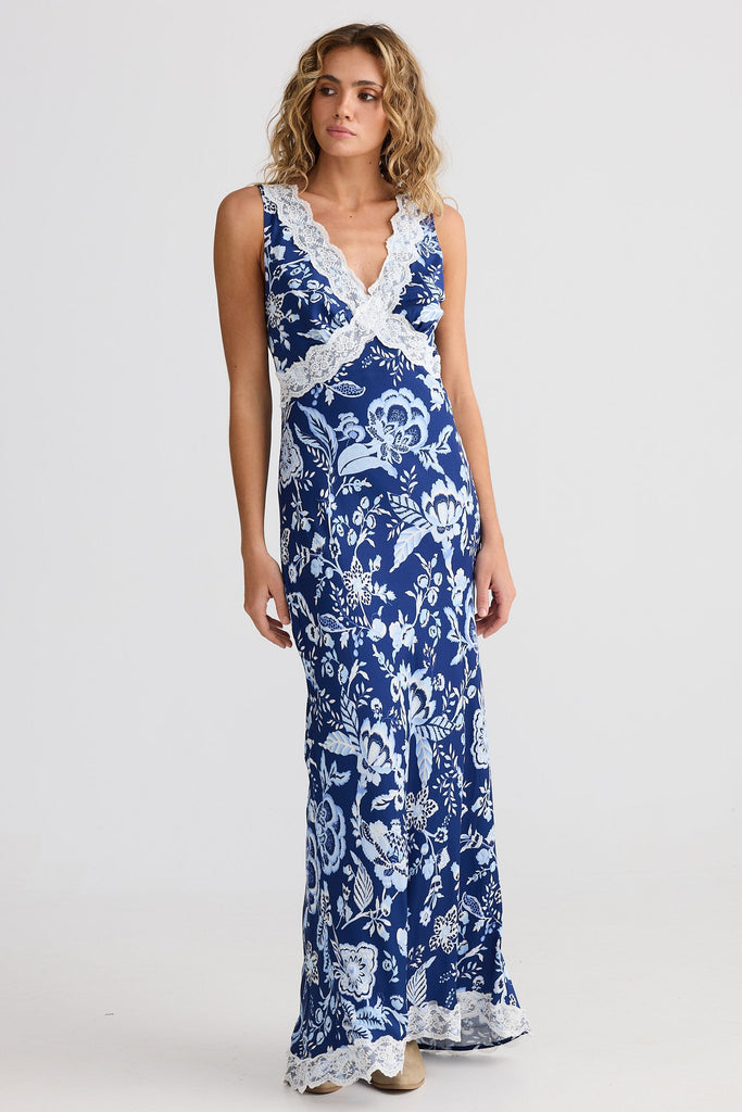 Woman wearing a blue floral dress with white lace details on a white background