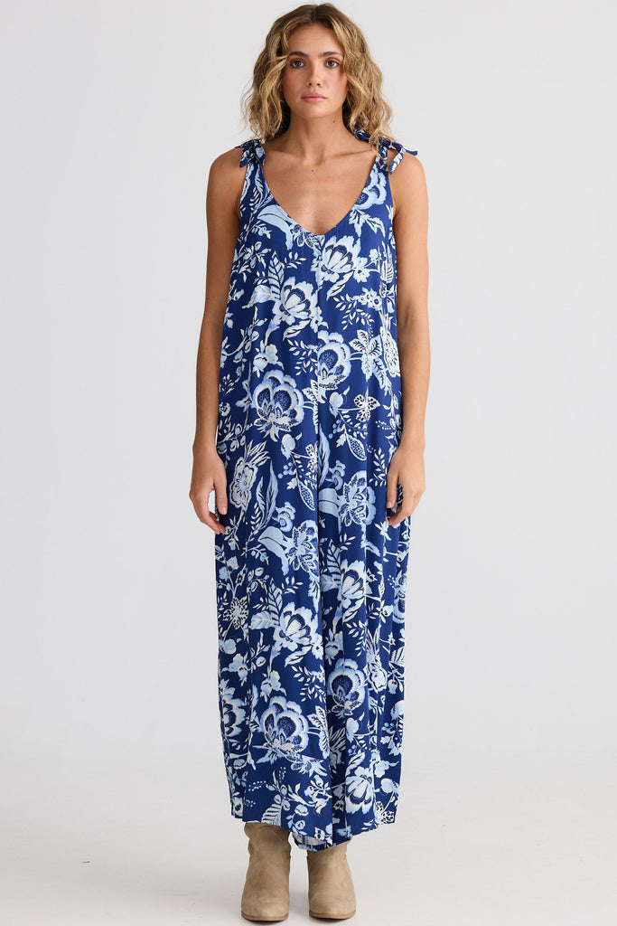Woman wearing a blue floral jumpsuit on a white background