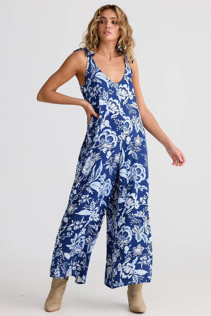 Woman wearing a blue floral jumpsuit on a white background