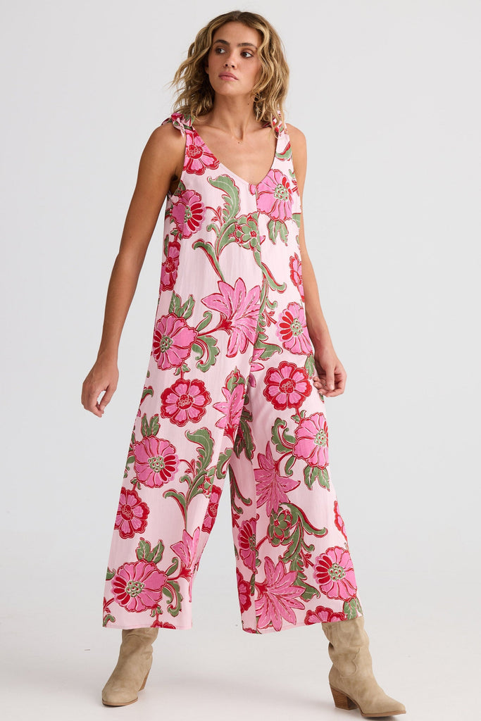 Woman wearing a pink floral jumpsuit on a white background