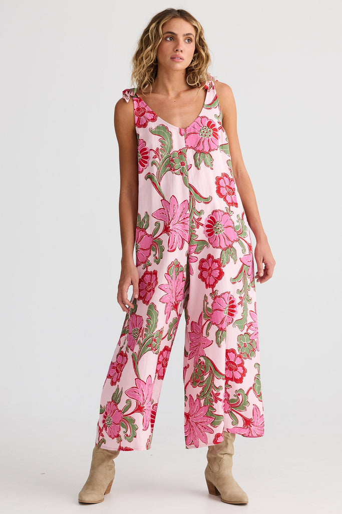 Woman wearing a pink floral jumpsuit on a white background