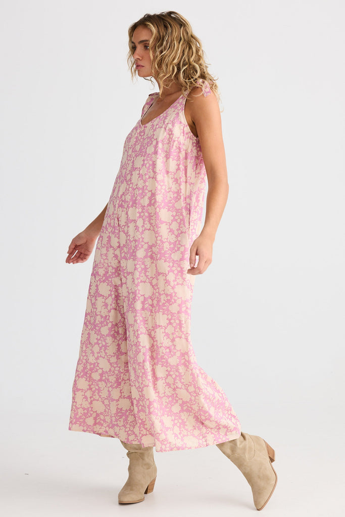 Woman wearing a pink floral jumpsuit on a white background