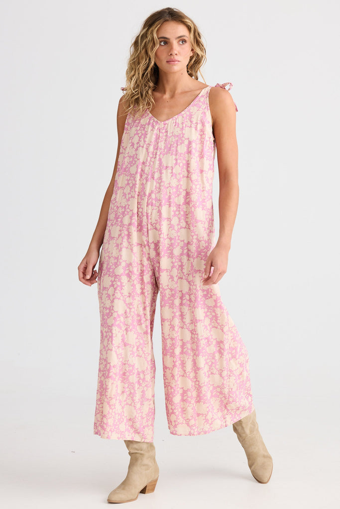 Woman wearing a pink floral jumpsuit on a white background
