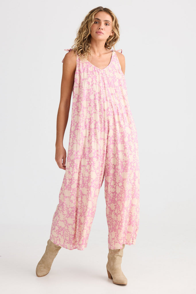 Woman wearing a pink floral jumpsuit on a white background