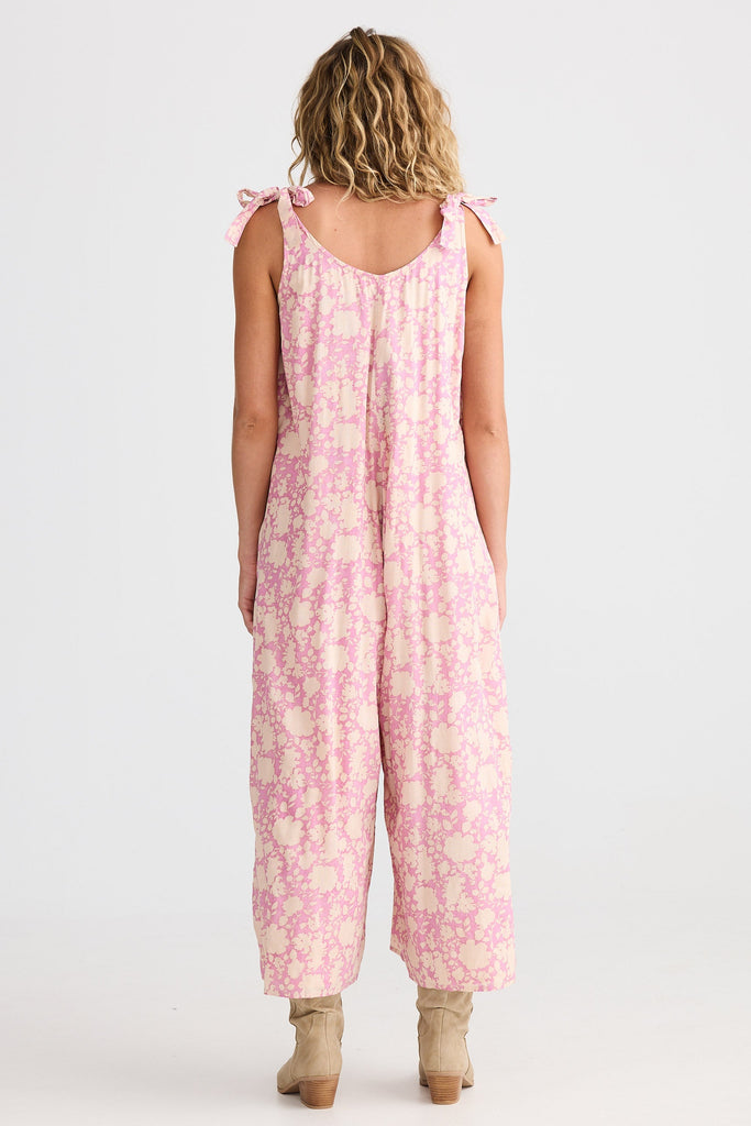 Person wearing a pink floral jumpsuit on a white background