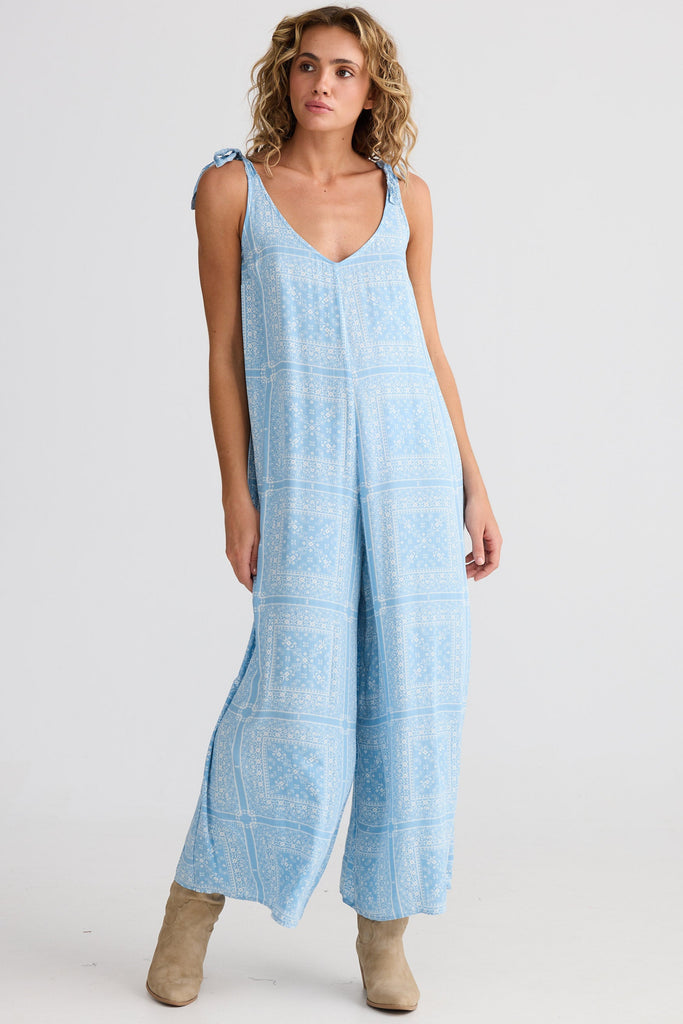 Woman wearing a light blue patterned jumpsuit on a white background