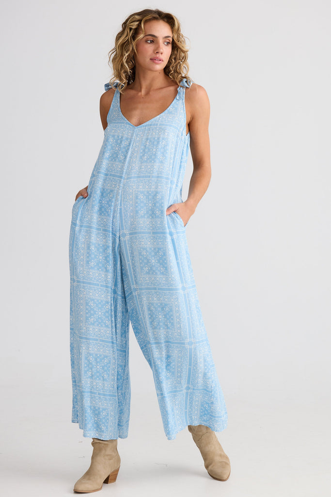 Woman wearing a light blue patterned jumpsuit on a white background
