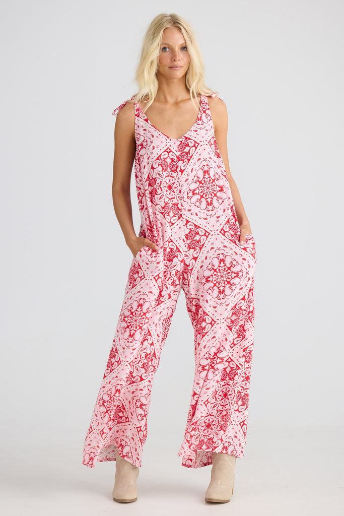 Woman wearing a red and white paisley jumpsuit on a white background
