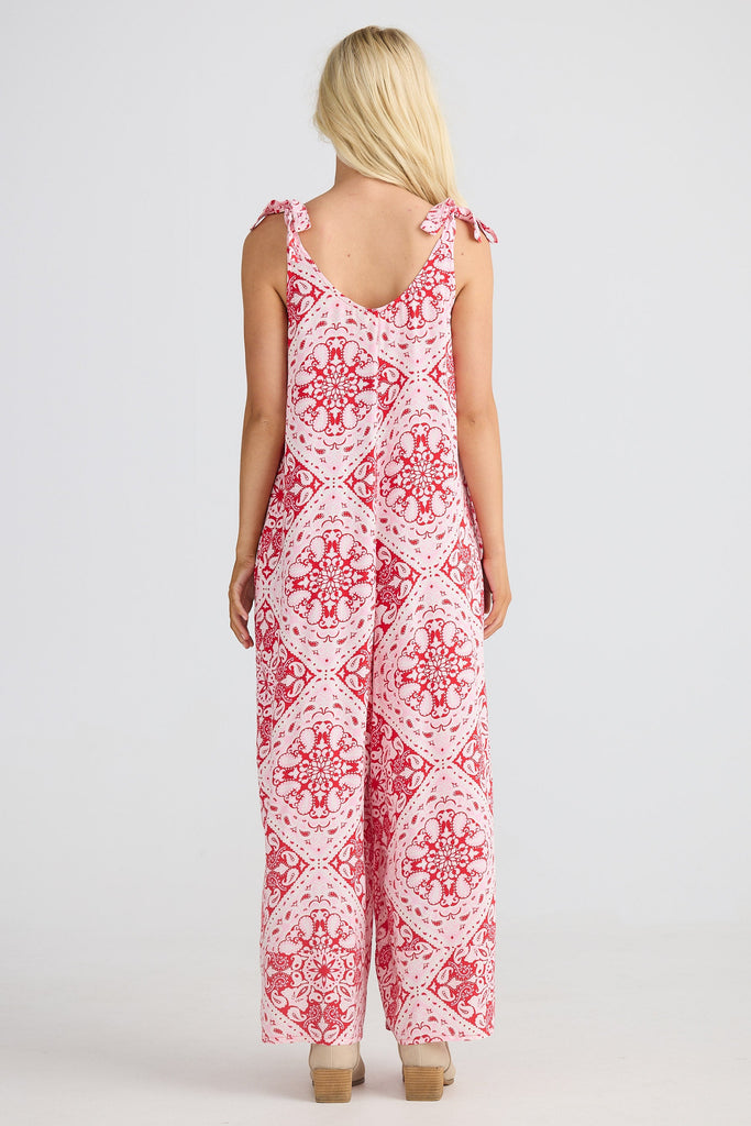 Woman wearing a red and white paisley jumpsuit on a white background