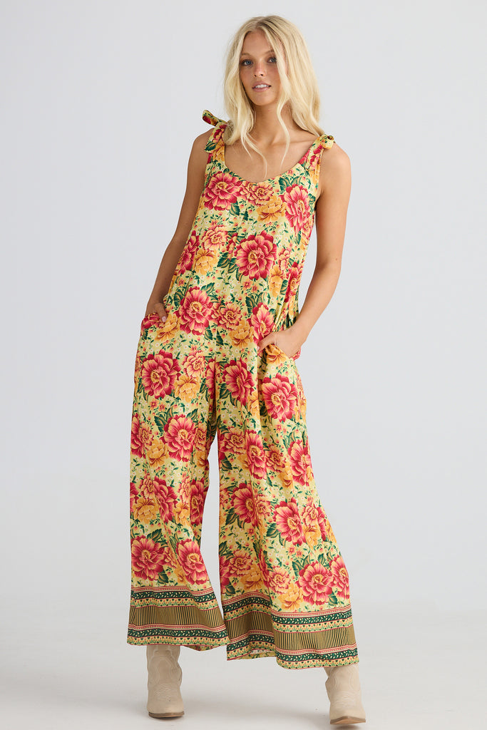Woman wearing a colorful floral jumpsuit on a plain background