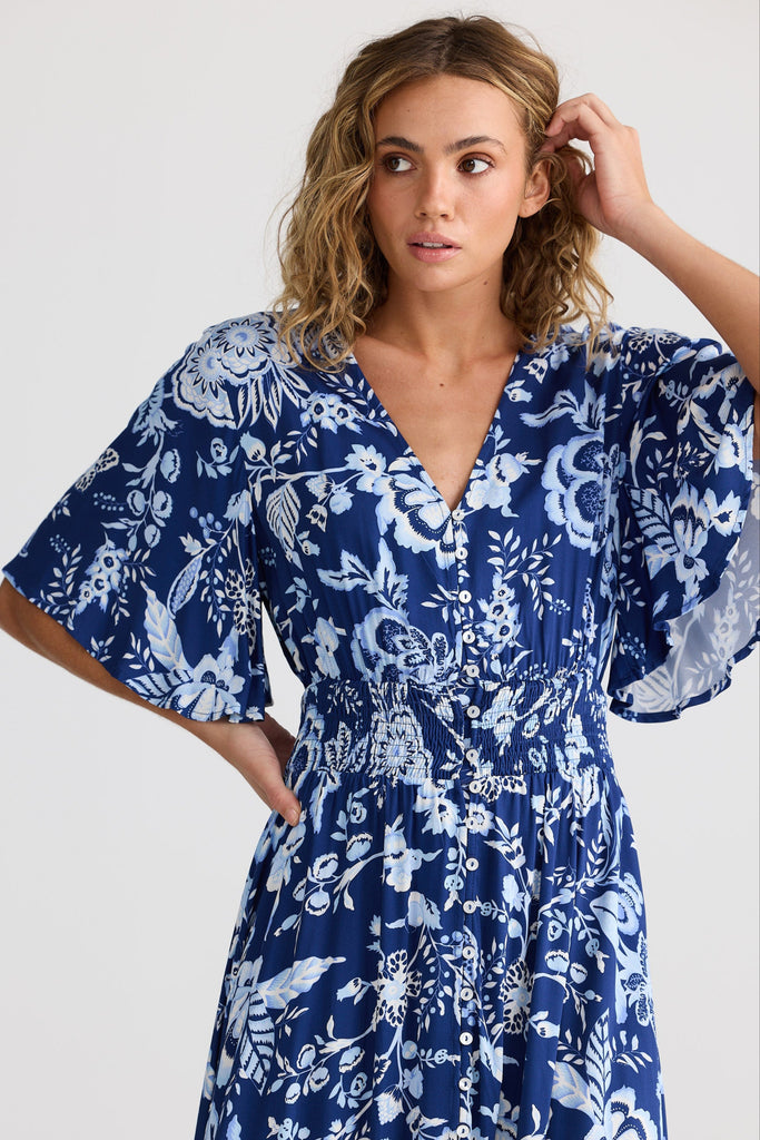Woman wearing a blue floral dress against a white background