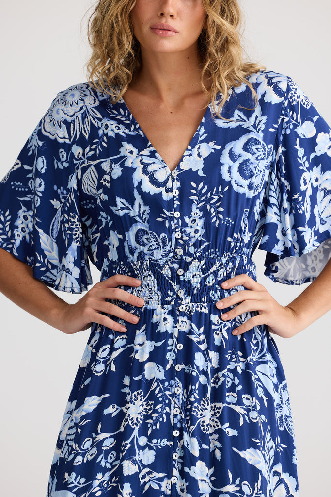 Woman wearing a blue floral dress against a white background