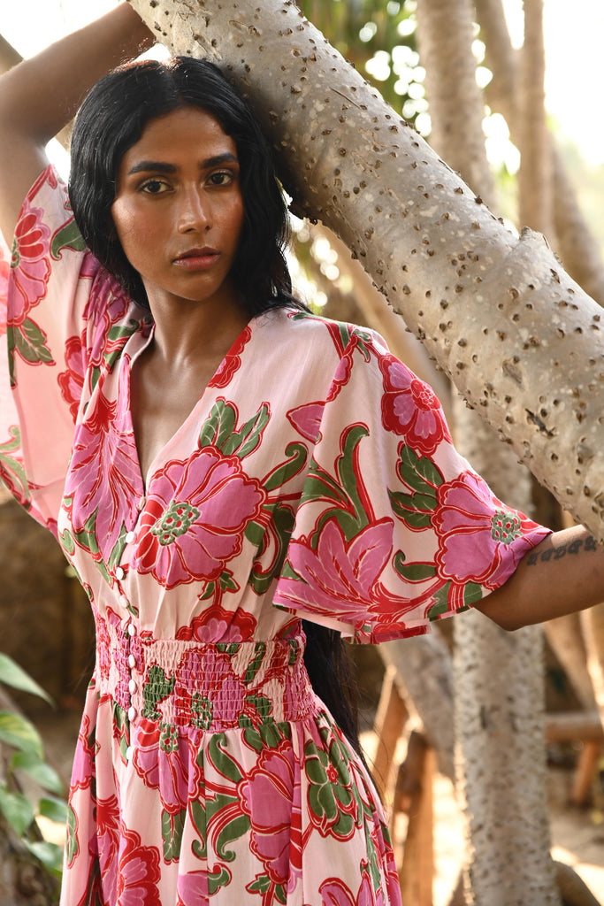 Woman in a floral dress leaning against a tree